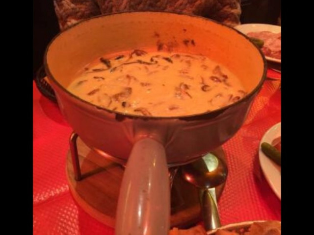 Fondue au fromage et aux champignons dans un caquelon sur nappe rouge