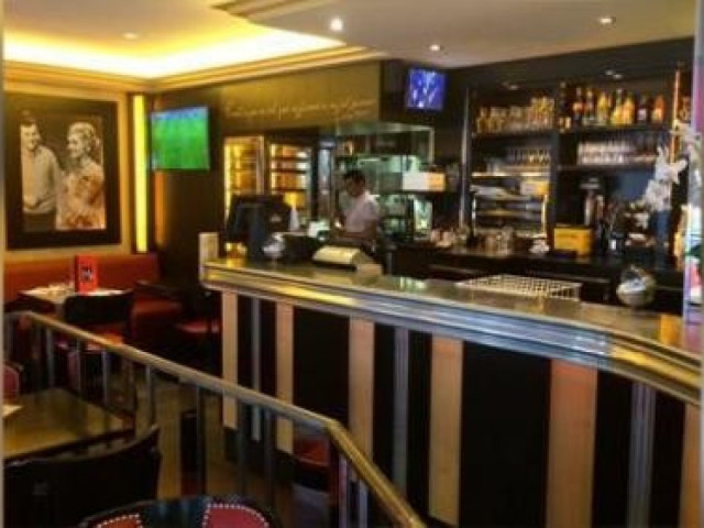 Bar moderne avec comptoir noir et or, mobilier rouge, ambiance lounge élégante